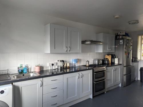 a kitchen with white cabinets and stainless steel appliances at Stunning 3Bed Seaview Downs National park House in Rottingdean