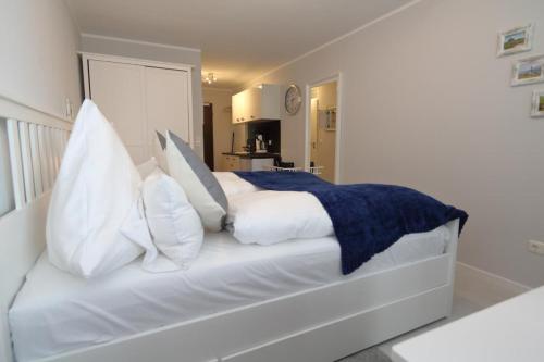 um quarto com uma cama branca com almofadas em Haus am Meer14 - App 129WB em Westerland