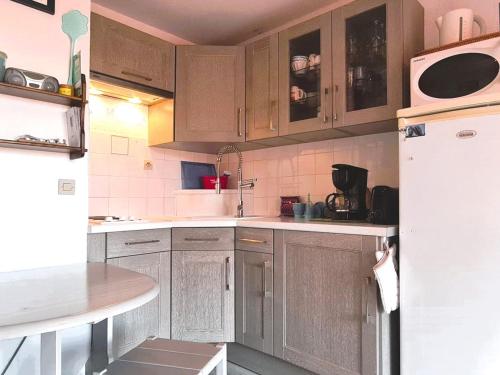 une cuisine avec des armoires en bois et un réfrigérateur blanc dans l'établissement Joli T2 avec balcon vue mer et parking à Collioure - FR-1-309-433, à Collioure