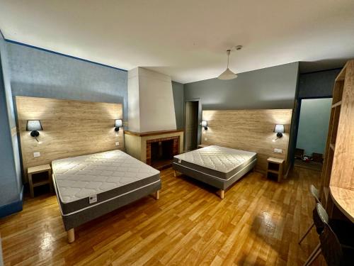ヴィック・フェザンサックにあるHotel Le D'artagnanのベッド2台と暖炉付きの広い客室です。