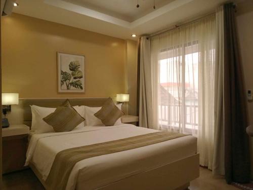 a bedroom with a large bed and a large window at Casa Marta Hotel in Iloilo City