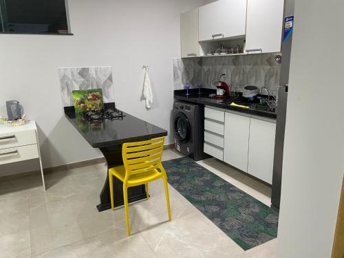 a kitchen with a table and a yellow chair at 3 Conforto próximo ao Forum in Manaus