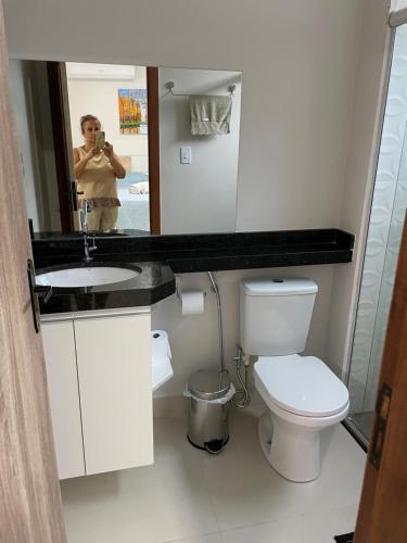 a person taking a picture of a bathroom with a toilet at 3 Conforto próximo ao Forum in Manaus