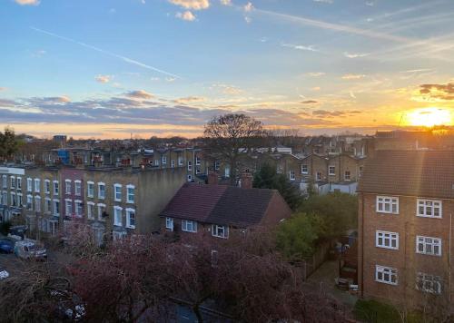 a view of a city with buildings and the sunset at Bright flat in Stoke Newington in London