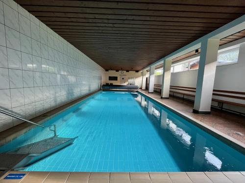 een zwembad met blauw water in een gebouw bij 3-Room Apartment with sauna and pool & walk to slopes in Saalbach Hinterglemm