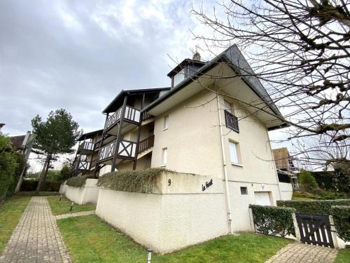 un grand bâtiment blanc avec une clôture devant lui dans l'établissement STUDIO AVEC TERRASSE PLEIN SUD - RÉSIDENCE LE FENIL AVENUE DE VERDUN A CABOURG, à Cabourg