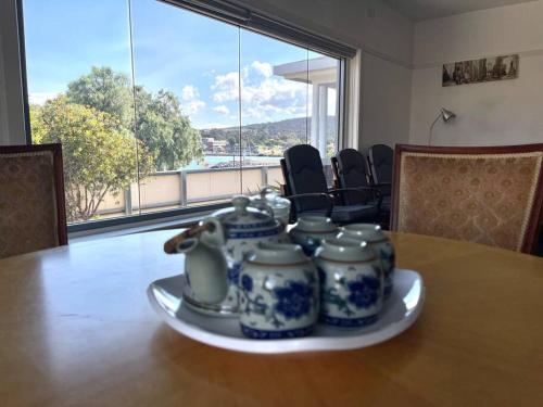 a table with four blue and white jars on a plate at Beach Cottage in Bellerive