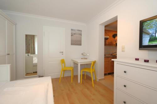 eine Küche mit einem Tisch und 2 gelben Stühlen in der Unterkunft Haus sarah 08 in Westerland