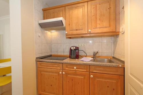 eine kleine Küche mit Holzschränken und einem Waschbecken in der Unterkunft Haus sarah 08 in Westerland