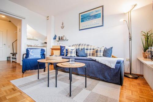 uma sala de estar com um sofá azul e duas mesas em Atlantik 23 -Standnahe Ferienwohnung em Wenningstedt