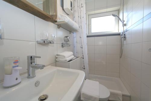 ein weißes Bad mit einem Waschbecken und einem WC in der Unterkunft Kiebitz-Nordseebrise - Wenningstedt in Wenningstedt-Braderup