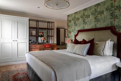 a bedroom with a large bed with a green wall at The Bridge Hotel in Chertsey
