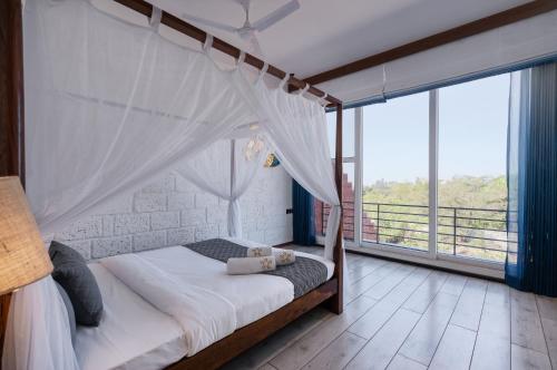a bedroom with a canopy bed and large windows at SaffronStays Calvin - 3 Bedroom Pool Villa In Lonavala in Lonavala