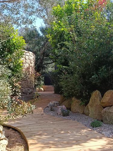 a garden with a walkway with rocks and trees at Hôtel Les Suites Du Maquis in Bonifacio