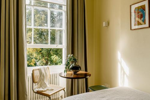 a bedroom with a window and a table and a chair at Mason & Fifth, Primrose Hill in London