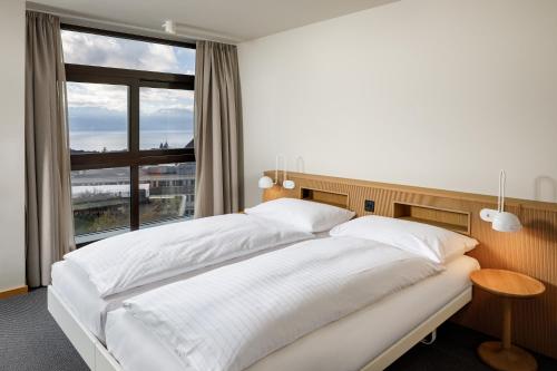 a white bed in a room with a large window at Alpha by Fassbind in Lausanne