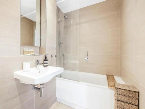 a white bathroom with a sink and a bath tub at Pass The Keys Charming 2 - Bed Apartment in Historic Drapery Modern - Comfort in Central London in London