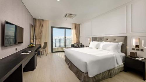 ein Hotelzimmer mit einem großen Bett und einem Schreibtisch in der Unterkunft GOLDEN APARTMENT With SEA VIEW in Đà Nẵng