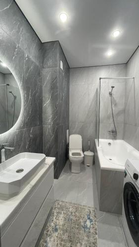 ein Badezimmer mit einem Waschbecken, einem WC und einer Badewanne in der Unterkunft Bekzat Apartment in Atyrau