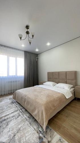 a bedroom with a large bed and a large window at Bekzat Apartment in Atyrau