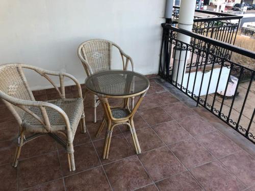 2 chaises et une table en verre sur un balcon dans l'établissement Μεζονέτα Χιόνα, à Chios