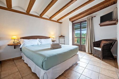 a bedroom with a bed and a chair and a window at Cal Tous, La Socarrimada in Rojals