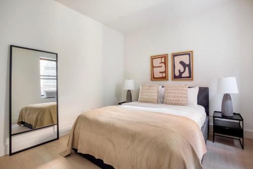 een witte slaapkamer met een bed en een spiegel bij Blueground Chelsea elevator wd nr 8th Ave NYC-1449 in New York