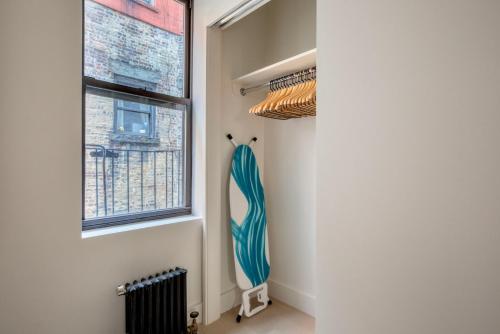 a room with a surfboard on the wall next to a window at Blueground Chelsea elevator wd nr 8th Ave NYC-1449 in New York