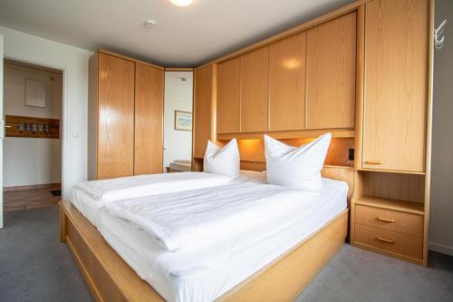 een slaapkamer met een groot wit bed en houten kasten bij App. Bagehorn 10 in Westerland