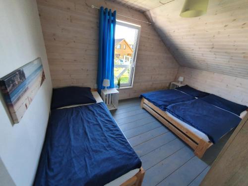 two beds in a small room with a window at Domki na Hamaku in Władysławowo