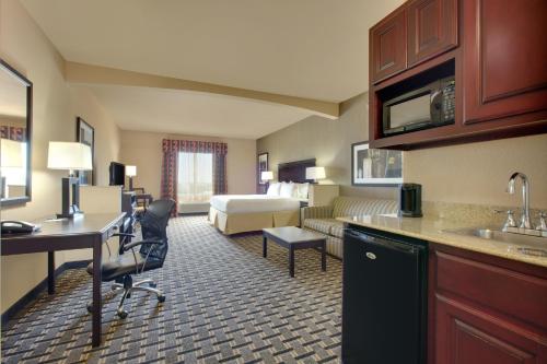 a hotel room with a kitchen and a bedroom at Holiday Inn Express Hotel & Suites Ennis, an IHG Hotel in Ennis