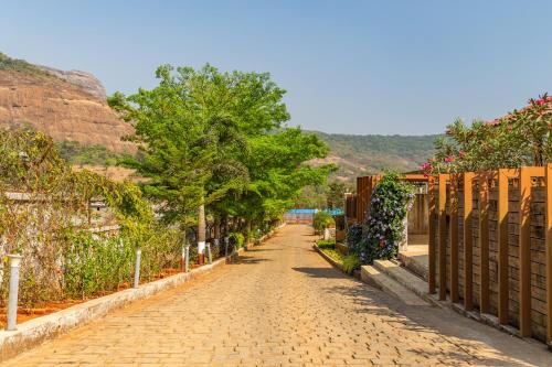 a cobblestone street with trees and a fence at Hillside Resort Lonavala - Pawna - Mountain View in Lonavala