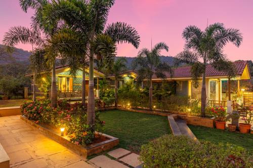 a house with palm trees and a garden at night at Hillside Resort Lonavala - Pawna - Mountain View in Lonavala