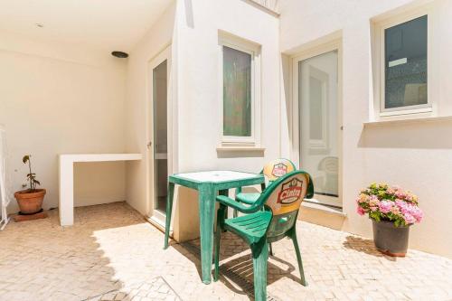a green table and chair in front of a house at Casa Hortas in Vila do Bispo