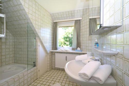ein weißes Badezimmer mit einem Waschbecken, einer Badewanne und einem Waschbecken in der Unterkunft Klagges - Keitum in Keitum