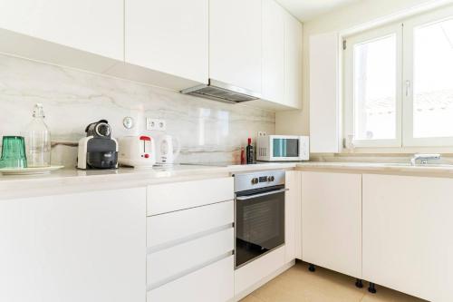 a white kitchen with white cabinets and appliances at Casa Hortas in Vila do Bispo