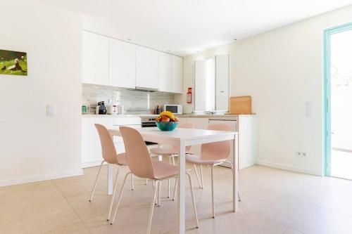 a white kitchen with a white table and chairs at Casa Hortas in Vila do Bispo