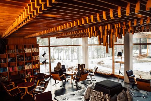 two women sitting in chairs in a library with a large window at Hotel Rantapuisto in Helsinki