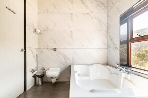 a white bathroom with a tub and a toilet at Hillside Resort Lonavala - Pawna - Mountain View in Lonavala