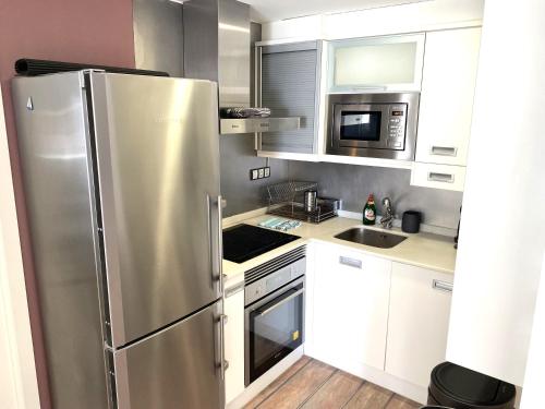 a kitchen with white cabinets and a stainless steel refrigerator at Beachfront and Charming Apartment in Mareny Blau