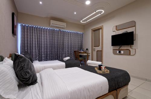 a hotel room with two beds and a flat screen tv at Exora Inn in Ahmedabad