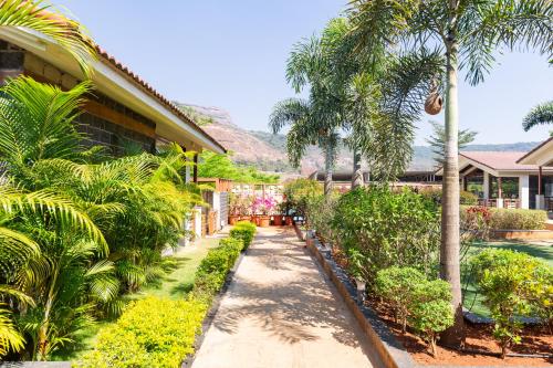 a garden with palm trees and a house at Hillside Resort Lonavala - Pawna - Mountain View in Lonavala