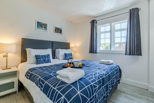 een slaapkamer met een blauw en wit bed en een raam bij The Faculty by Celador Apartments in Reading
