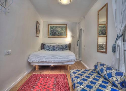 een kleine slaapkamer met een bed en een bank bij Courtyard Suite, Artists' Quarter, Tzfat in Safed