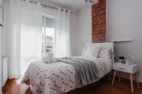 a white bedroom with a bed and a brick wall at tuGuest Dílar Apartment in Granada
