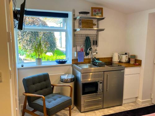 una cucina con lavandino e sedia accanto a una finestra di The Annexe a Bruton