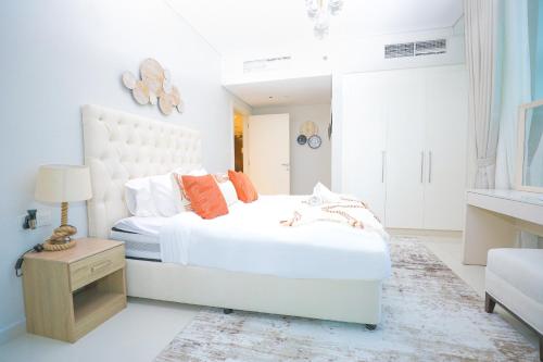 a white bedroom with a white bed with orange pillows at Business Bay 1BR Gem Luxe Living in Dubai