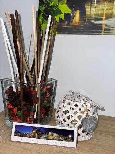 a vase with sticks and a picture on a table at RomaFatata: Intero appartamento in Rome