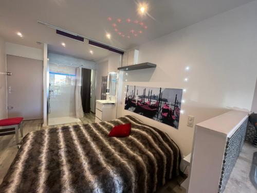 une chambre avec un grand lit avec un oreiller rouge dessus dans l'établissement Residence PORT NATURE by 8-HOMES vue Port, au Cap d'Agde