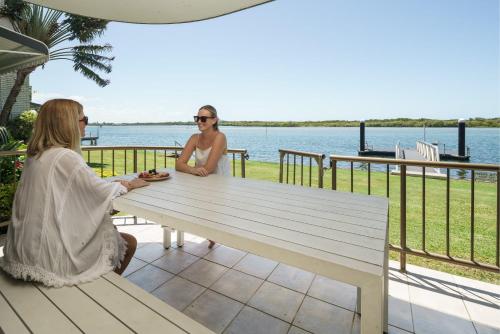 two women sitting at a picnic table near the water at River Front Escape, Short Walk to Ocean Street in Maroochydore